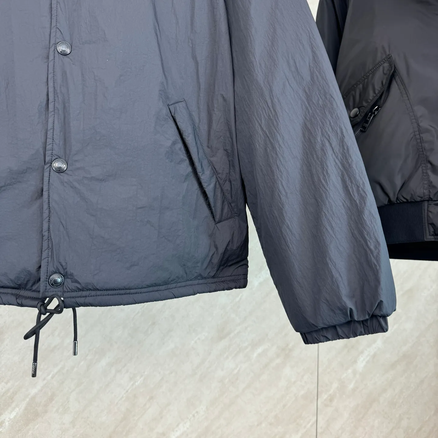 P670 25FW Ralph Lauren red label light cotton jacket (coach jacket) size s m l xl Fabric procurement: a combination of pragmatism and classic texture Material: high-density nylon taffeta Features: density is about 210T-300T, smooth and slightly matte surface, excellent windproof and waterproof performance (with DWR water-repellent treatment), strong wrinkle resistance and easy care, in line with the positioning of American casual "durable and practical".  Color: Classic dark black, using vat dyeing process (dye penetrates into the fiber), the color fastness reaches ISO level 4 or above to avoid fading or color transfer after washing.  2. Lining fabric Material: Lightweight cotton-polyester blended lining (65% Polyester + 35% Cotton) Function: Reduce friction between the fabric and inner clothing, improve wearing smoothness; blended material has both breathability and durability to avoid the stuffy feeling of pure nylon lining.  Version and cutting process Version: Classic Coach Jacket, loose version, slightly dropped shoulder line (shoulder width is 1-2cm wider than the standard version), length to the hips, and slightly tapered straight sleeves, taking into account both freedom of movement and casual style.  Embroidery technology: Polo horse logo on the left chest: flat satin stitch embroidery (satin embroidery), embroidery thread: 100% polyester high color fastness embroidery thread (the color number is consistent with the brand’s standard red color card), stitch density 12-15 stitches/cm, the outline of the horse logo is clear, and the details of the rider and horse are burr-free.  Embroidery positioning: precise positioning through the template (12cm from the neckline and 8cm from the placket) to ensure left and right symmetry and centering.  Topstitching technology: The seams of the body are made of double-needle flat seams (needle pitch 3cm/10 needles), the stitches are smooth and straight, the stitching color is dark black (the same color as the fabric), and the stitch width is 0.5cm, which enhances firmness while forming simple decorative lines.  1. Main body splicing, splicing of the front placket and body: The placket is made of double-layer folding + flat seam splicing, with a thickness of about 0.3cm to ensure that the buttons are not easily deformed when fixed; the edges of the placket are cut with a hot knife to avoid burrs.  Sleeve panels are spliced ​​to the body: the armholes are spliced ​​with round-head keyhole machine seams + flat seams. After splicing, the armholes have a natural curvature and no sense of tightness during movement; the height of the sleeves is about 8-10cm, which is in line with the loose characteristics of casual jackets.  Main button: black urea resin button, matte surface treatment, buttonholes are hand-made keyholes (6 strands of cotton thread, keyhole density 8 stitches/mm), the edges of the eyelets are smooth and without burrs.  Collar buttons: The first button on the collar is a hidden button (diameter 12mm), which prevents the collar from opening and improves the neatness of wearing.